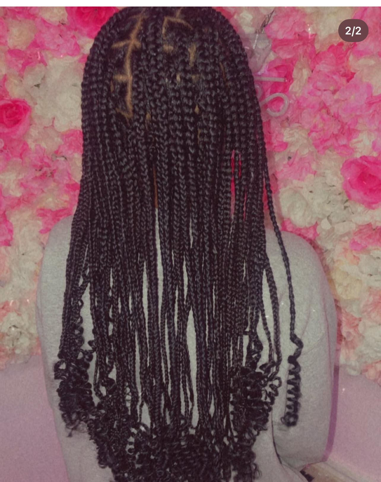 Long dark box braids with curly ends against a floral background