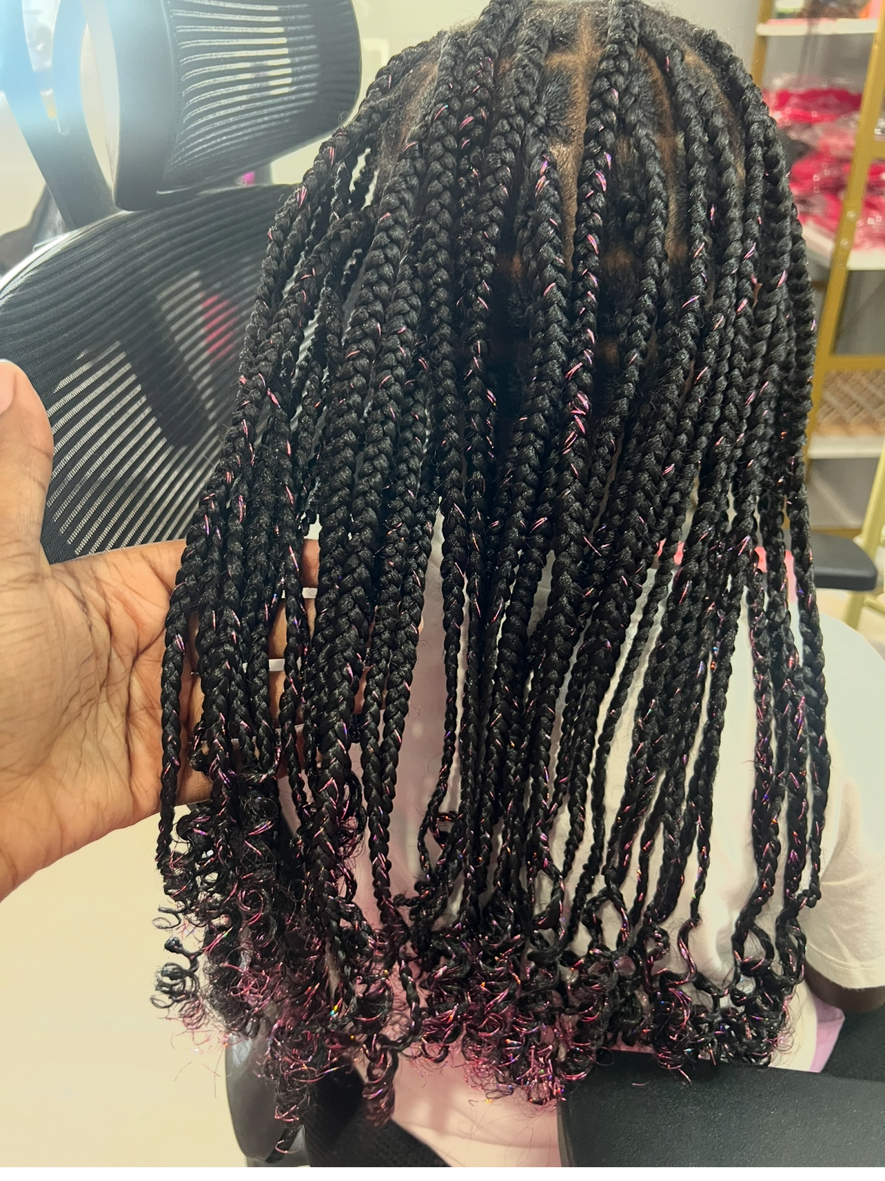 Long dark box braids with pink highlights and curly ends