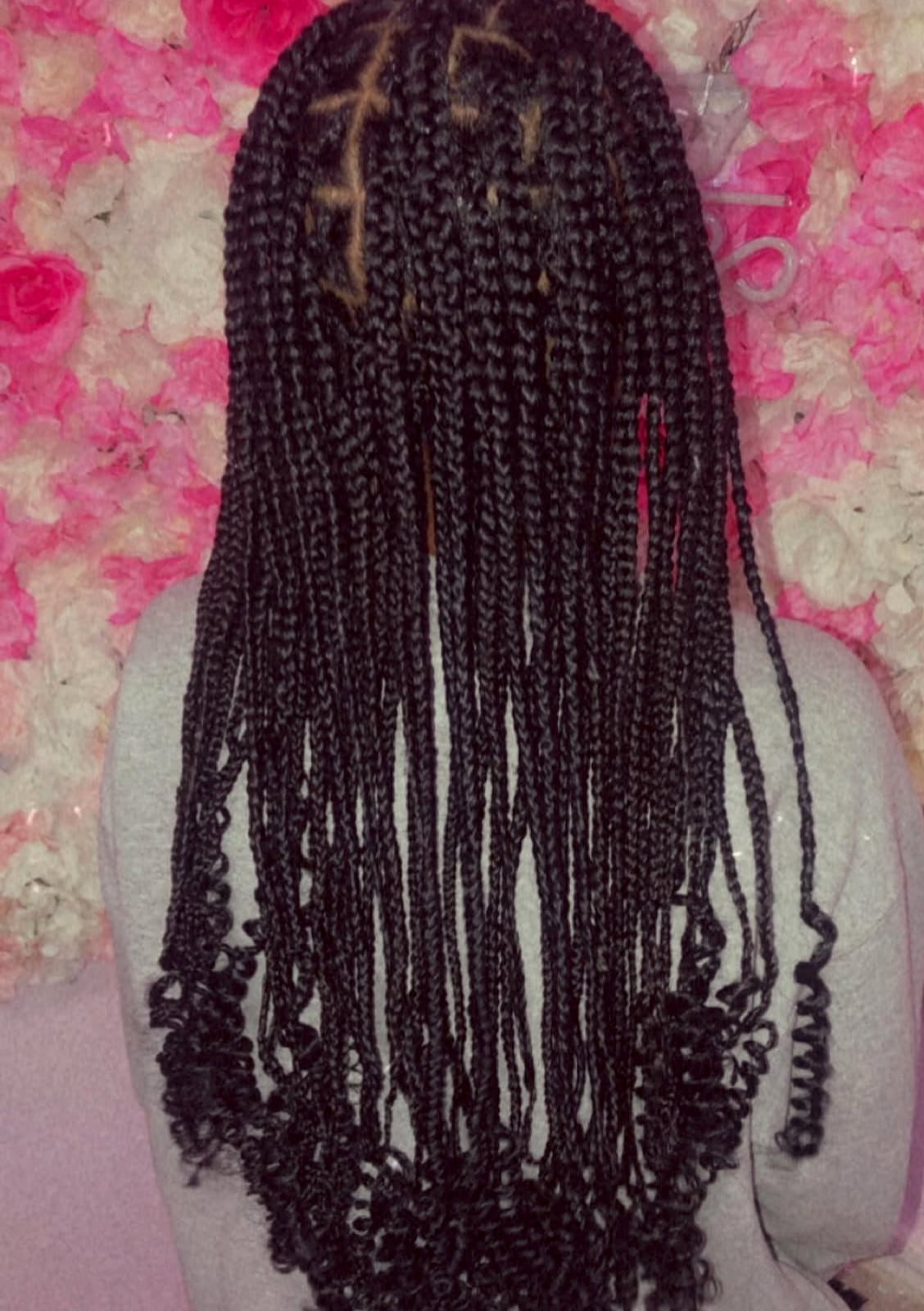 Long dark box braids with curly ends against a floral background