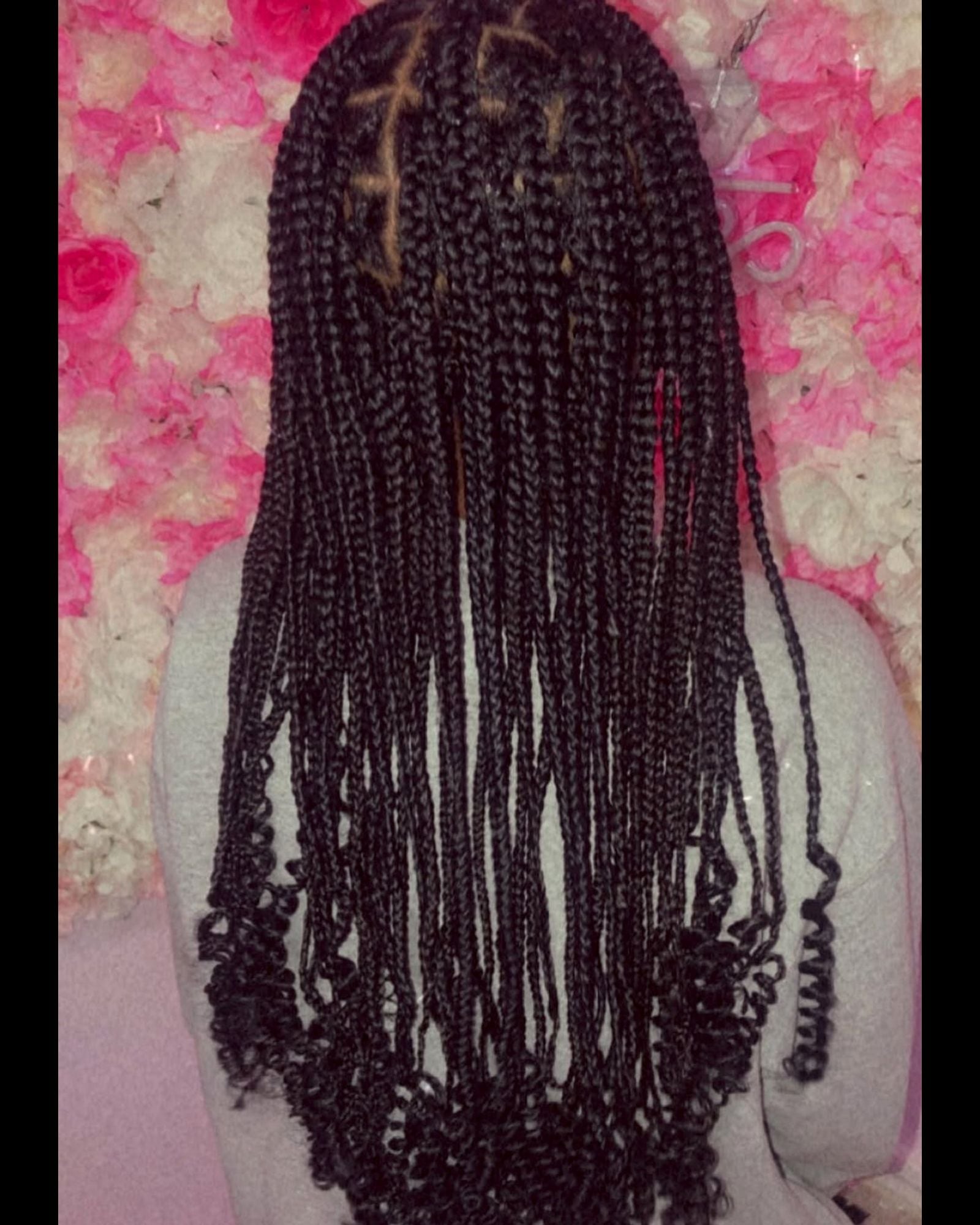 Long dark box braids with curly ends against a floral background