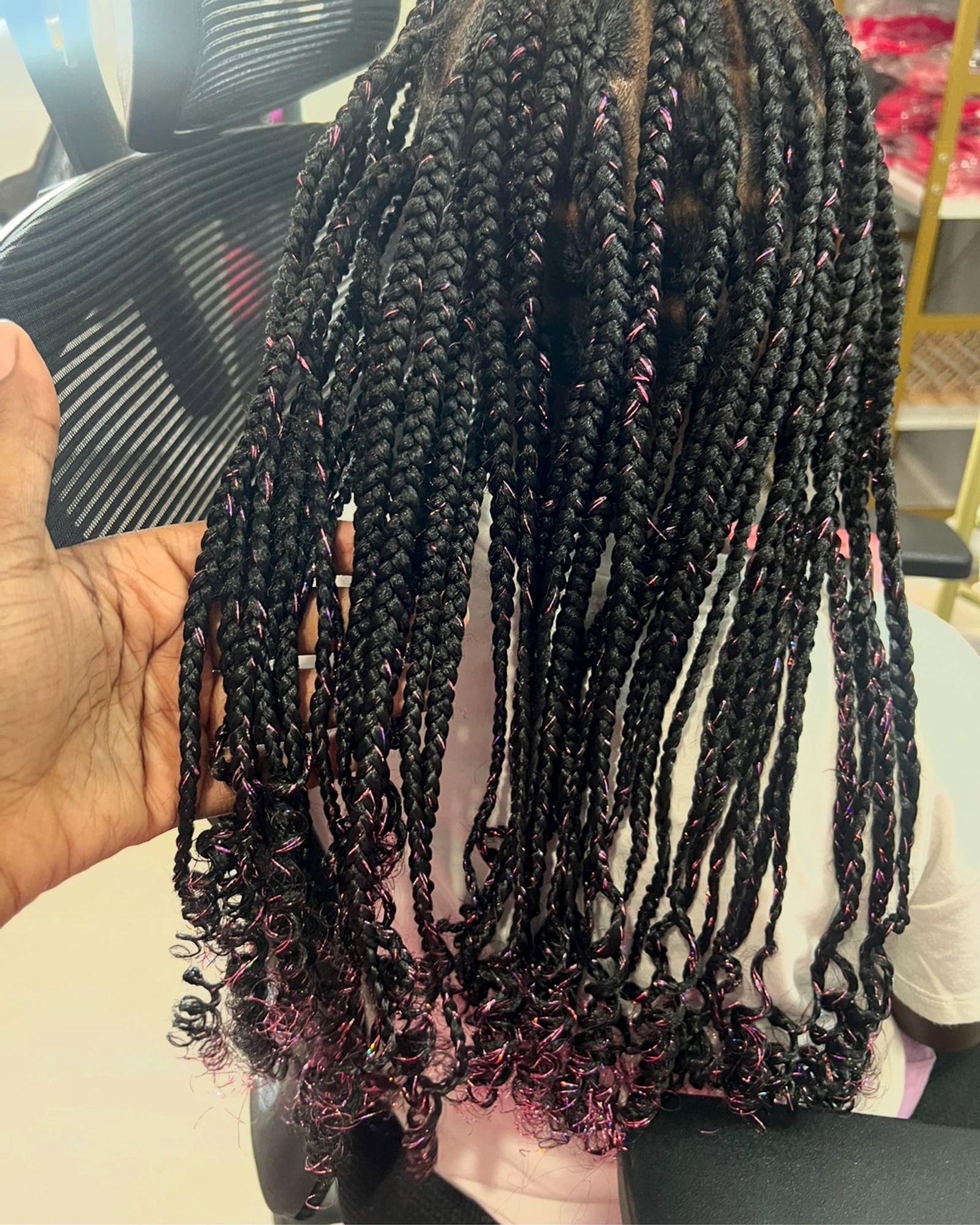 Long dark box braids with pink highlights and curly ends